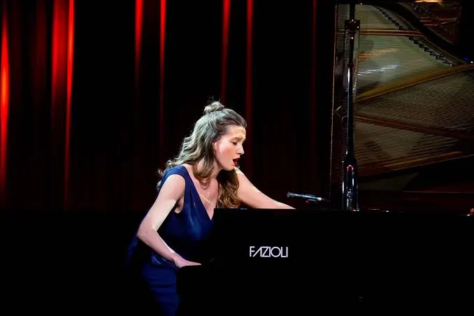 Rachel Fenlon wears a blue dress while playing the people on stage.